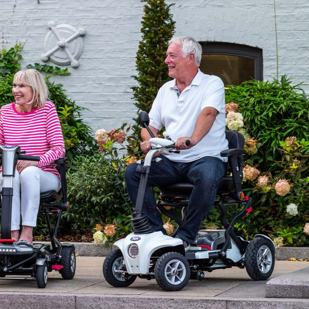 Showing the TGA Maximo Plus Mobility Scooter with a man driving it on a pavement.